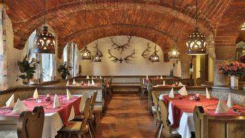 Un restaurante con arcos de ladrillo, mesas de madera y candelabros iluminados con velas.