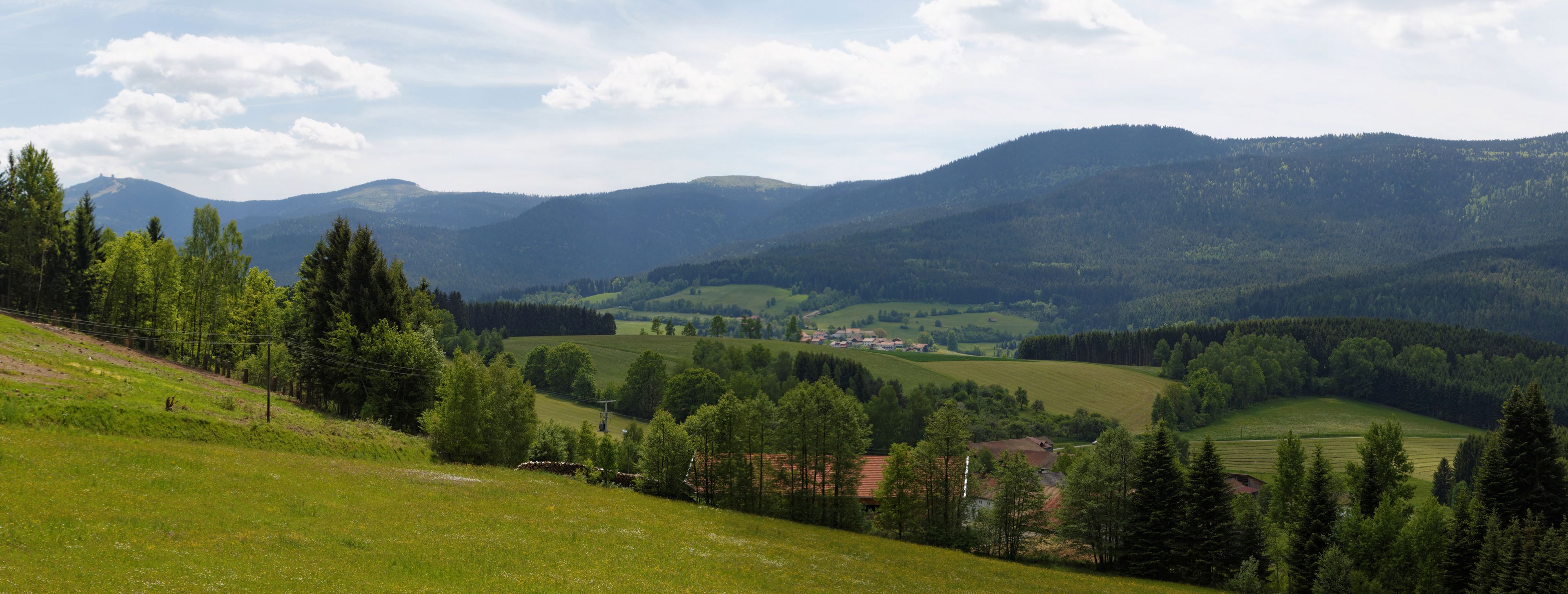 Una vista panorámica de un valle con colinas onduladas, un pequeño pueblo y bosques densos.