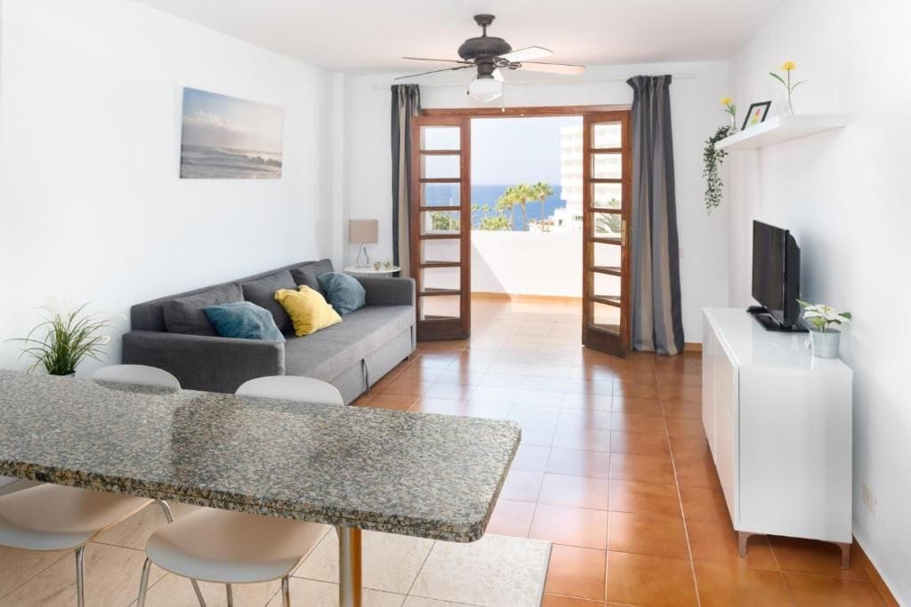 A modern living area with a sofa, dining table, and TV.