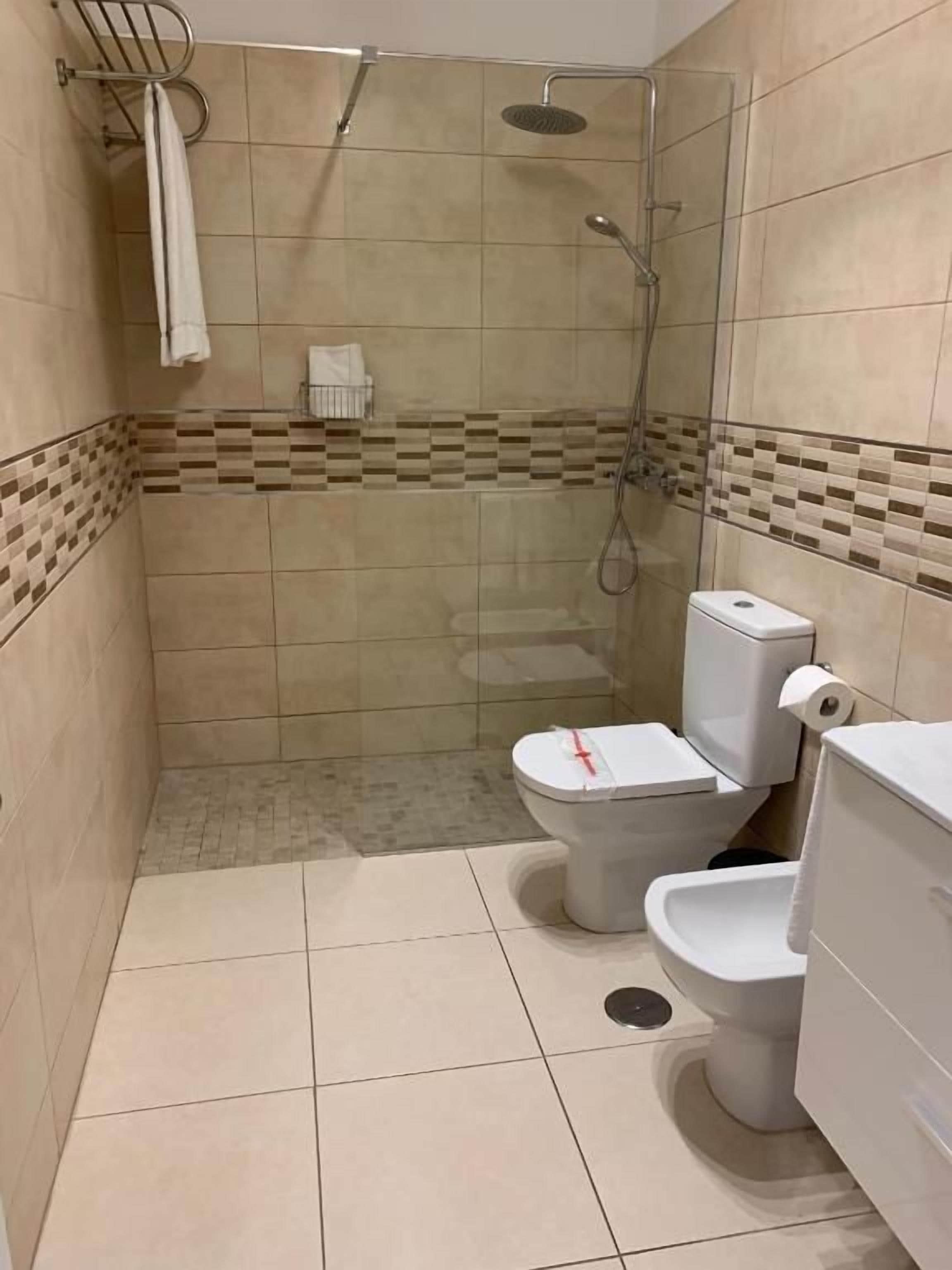 A small bathroom with a shower, toilet, and sink.