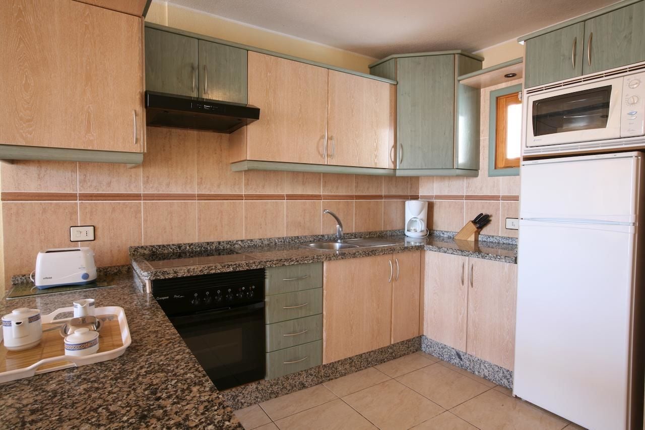Una cocina con encimeras de granito, lavavajillas, microondas y tostadora.