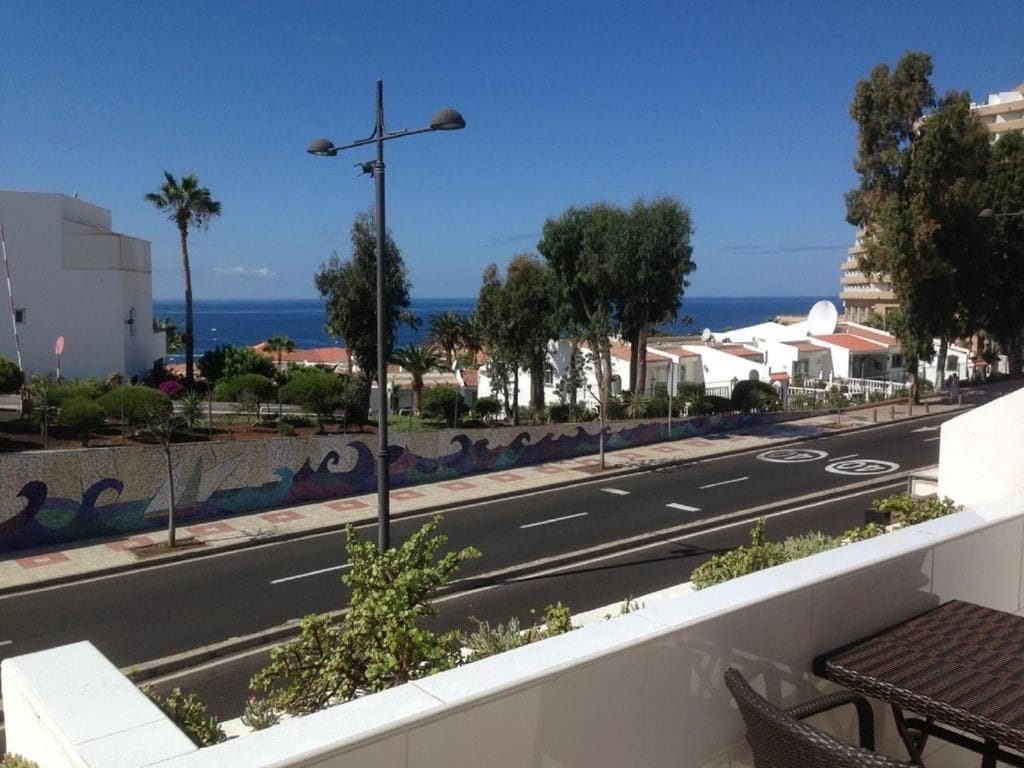 Una carretera costera con vistas al mar, un paseo peatonal y edificios con balcones.