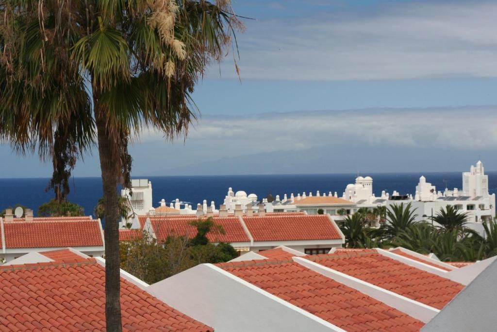 Un pueblo costero con techos de tejas rojas y edificios blancos, con vistas al mar.