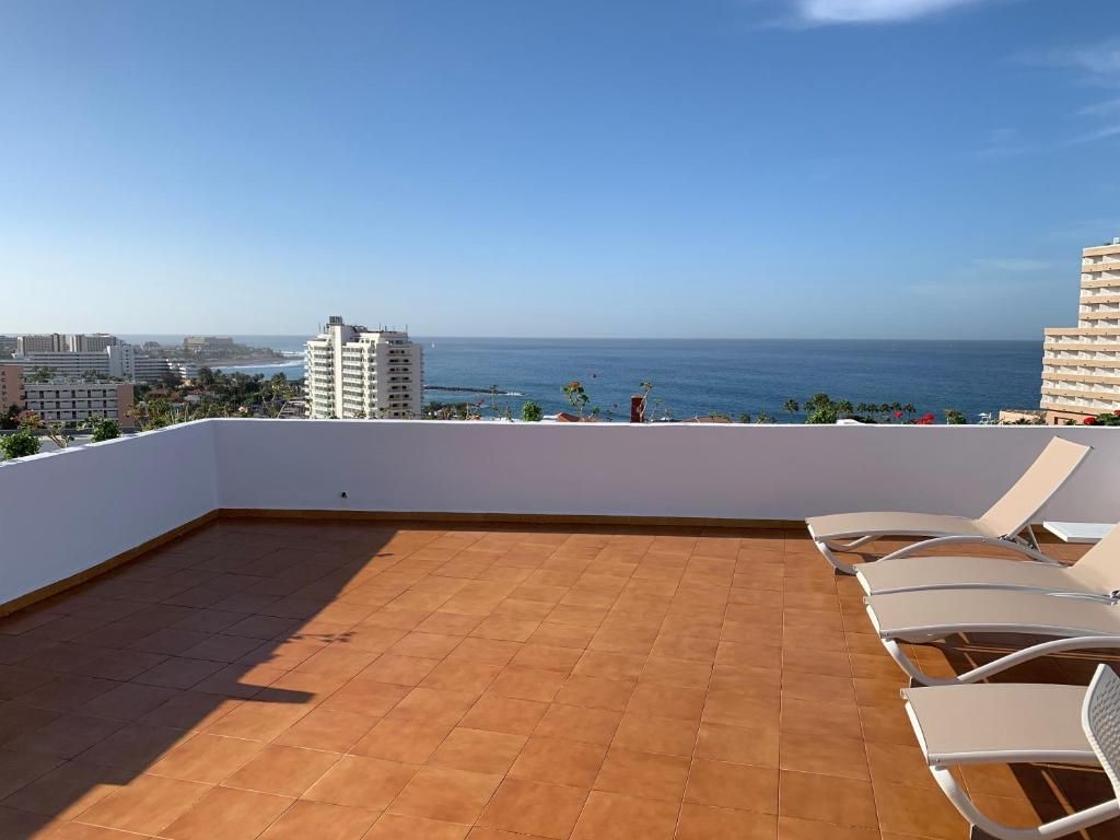 A rooftop terrace with a view of the ocean and cityscape.