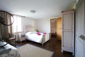 A bedroom with a bed, bedside tables, a chair, a mirror, and a wardrobe.