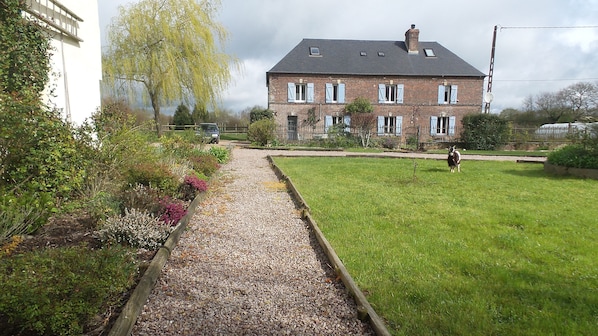 A brick house with a gravel pathway leading to a grassy yard.