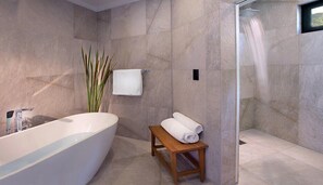 A modern bathroom with a freestanding bathtub, a wooden bench, and a glass-enclosed shower area.