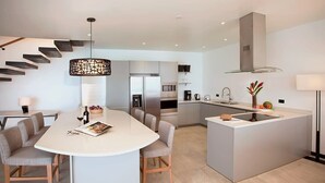 Una cocina moderna con una isla central, electrodomésticos integrados y una escalera.