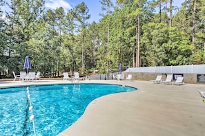 A swimming pool with lounge chairs and umbrellas, surrounded by a forested area. - Keowee Keys Home w/ Mountains View & Lake Access! (Salem)