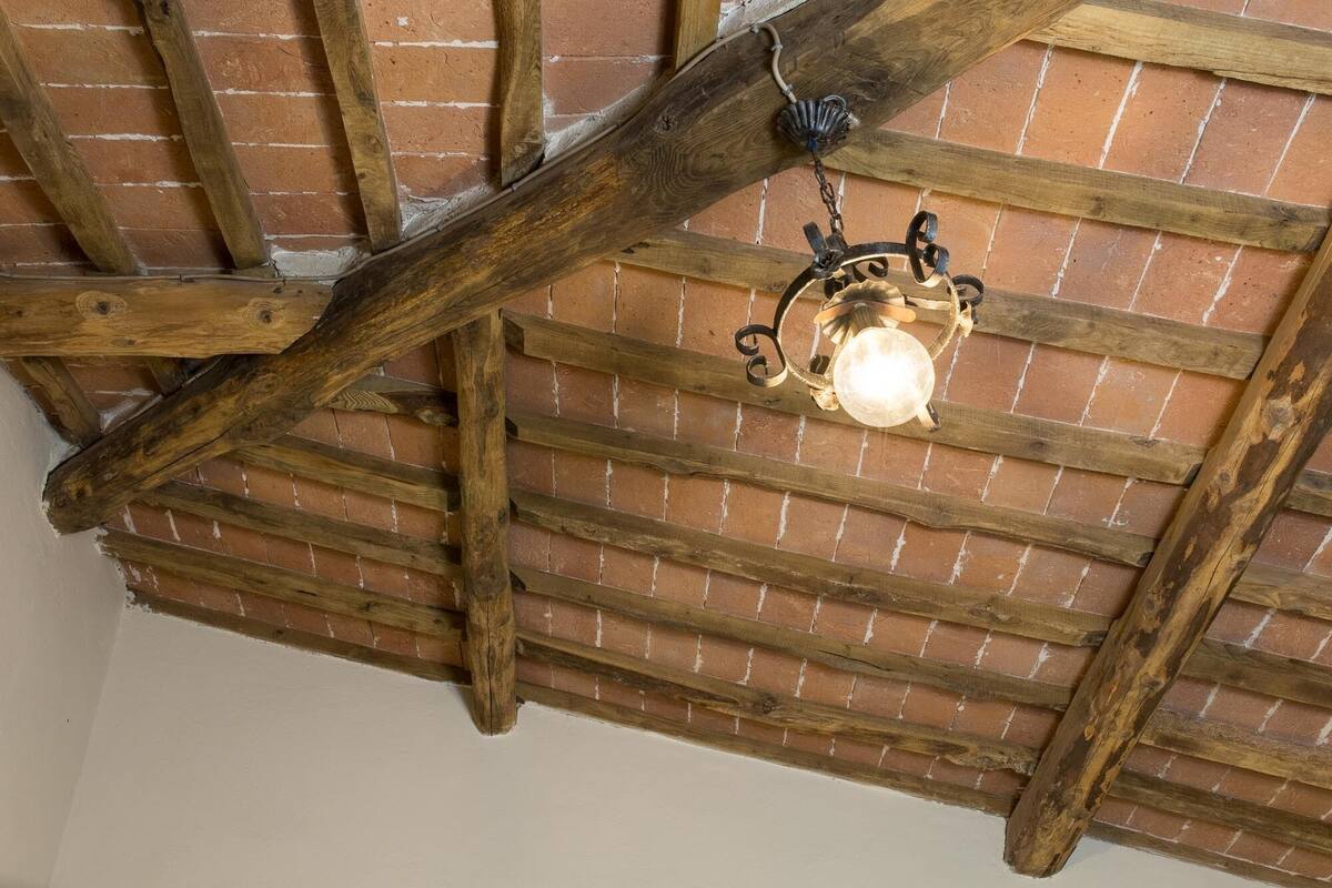 A rustic ceiling with exposed wooden beams and a hanging light fixture.