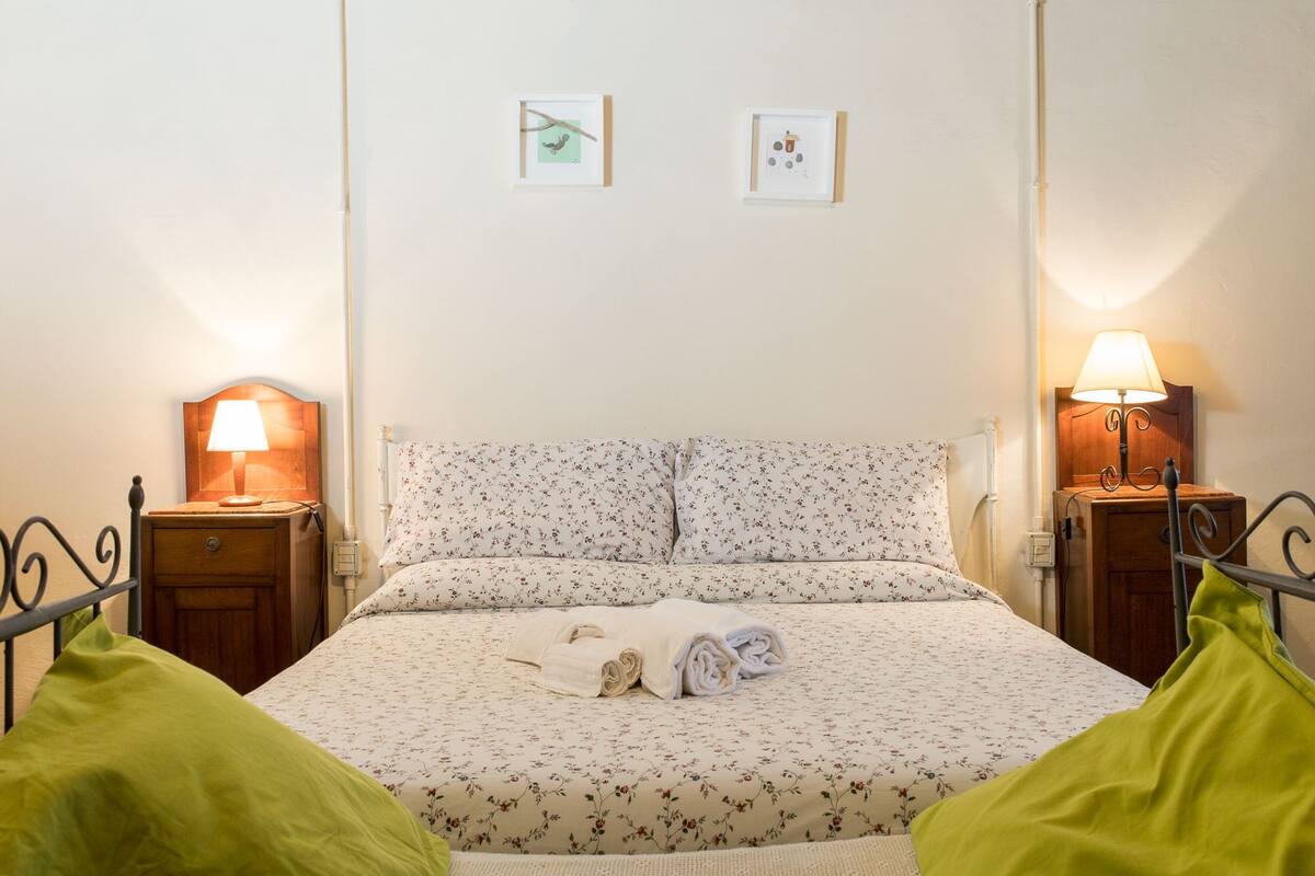 A neatly made bed with floral bedding and two bedside lamps.