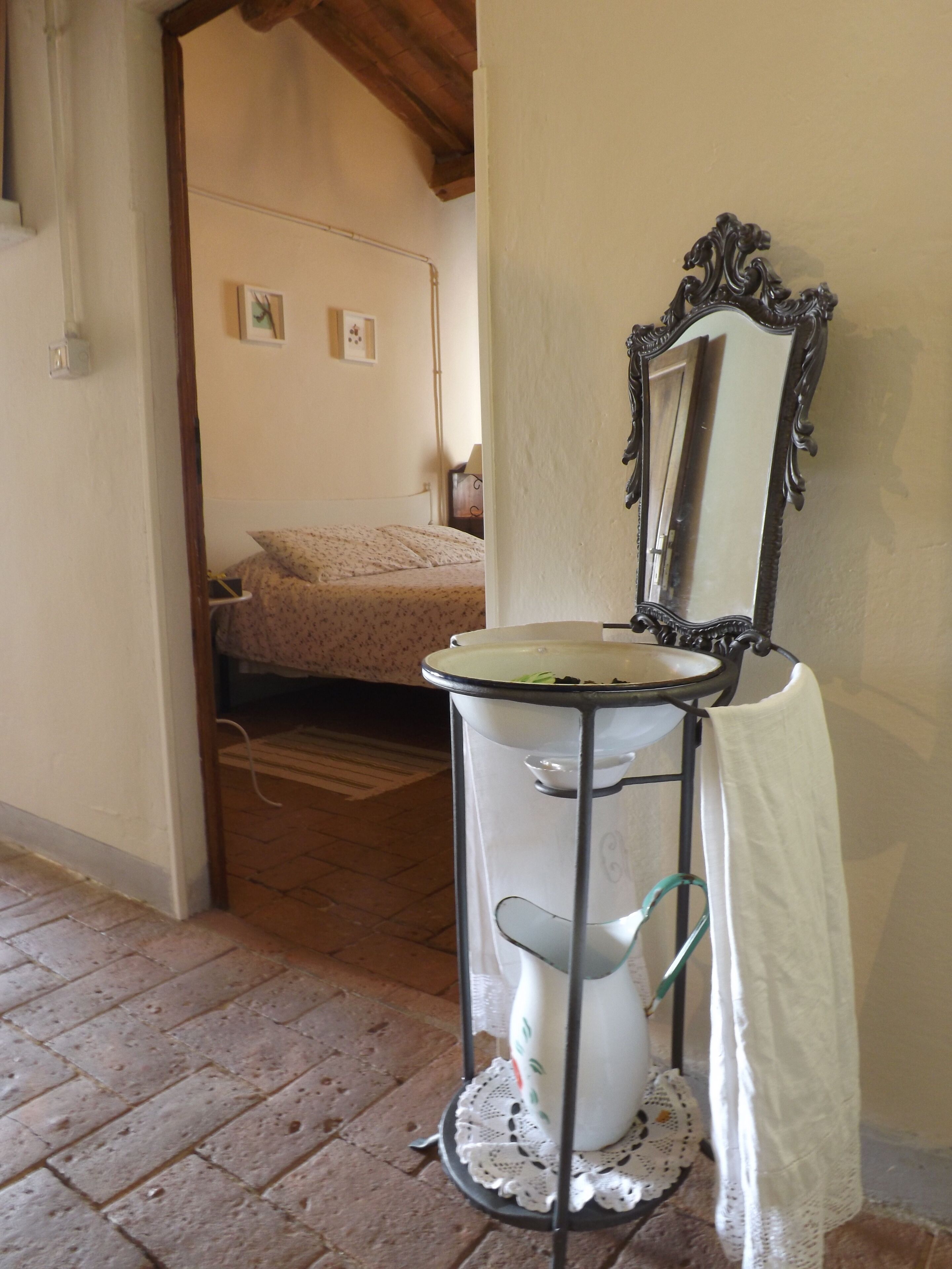 Un baño con un lavabo blanco, un espejo con marco decorativo y una toalla colgada en un perchero.