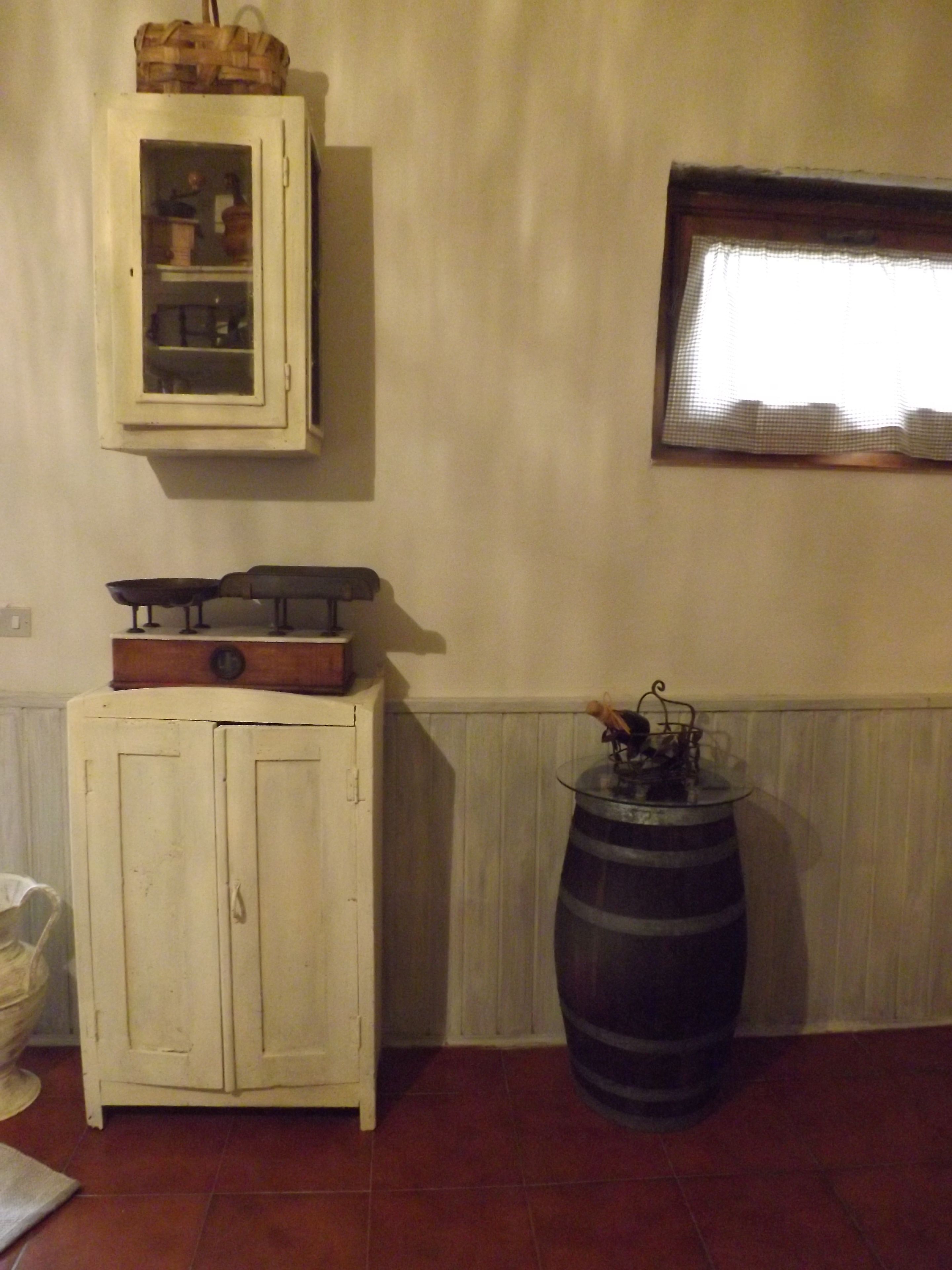 Ein Zimmer mit einem weißen Schrank, einem großen Fass und einem Fenster mit Rollläden.