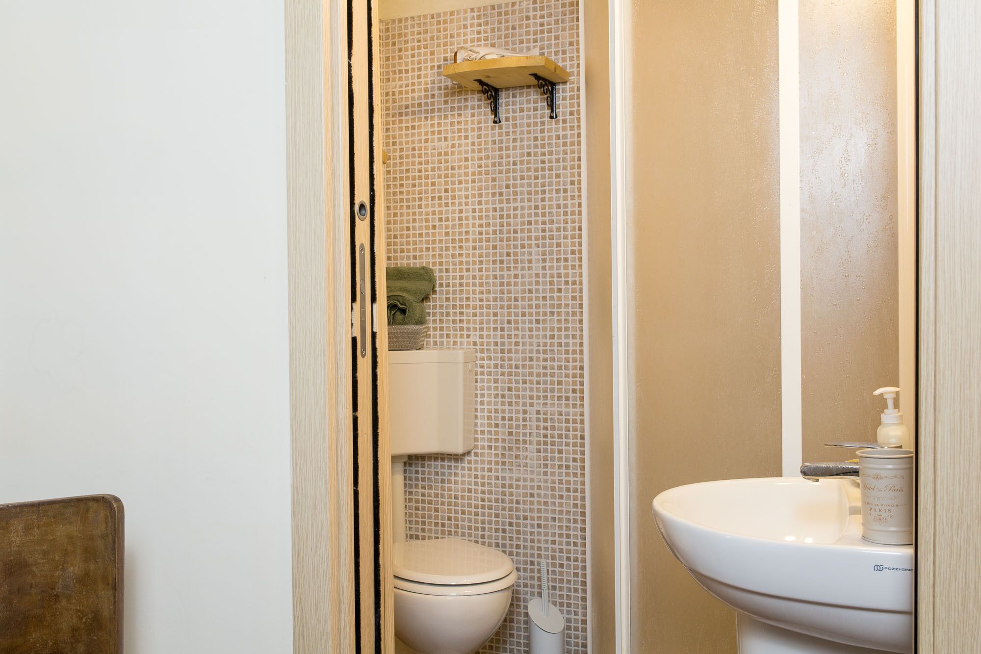 Un bagno con un water, un lavandino e uno scaffale con un asciugamano.