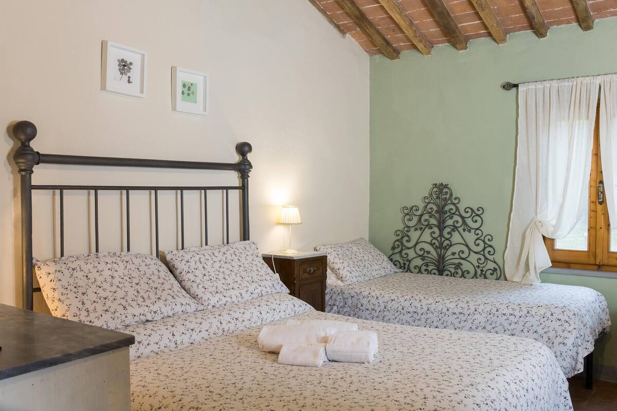 A bedroom with two beds, a nightstand, a lamp, and a decorative metal headboard.