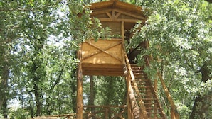 Een houten uitkijktoren met een trap, omringd door bomen.