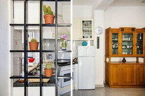 A kitchen with a black metal shelf unit, a white refrigerator, and wooden cabinets. - Manzoni Apartment Le Castella (Le Castella)