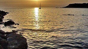 A sunset over a calm sea with rocks on the shore and a buoy in the water. - Manzoni Apartment Le Castella (Le Castella)
