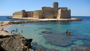A historic fortification with clear waters and rocky shores, surrounded by tourists. - Manzoni Apartment Le Castella (Le Castella)