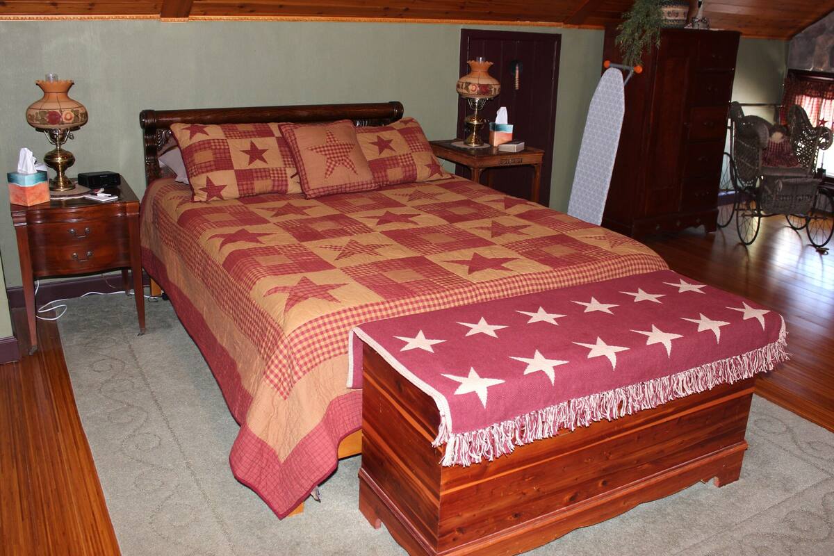 A bedroom with a wooden bed, a nightstand with a lamp, and a chair.
