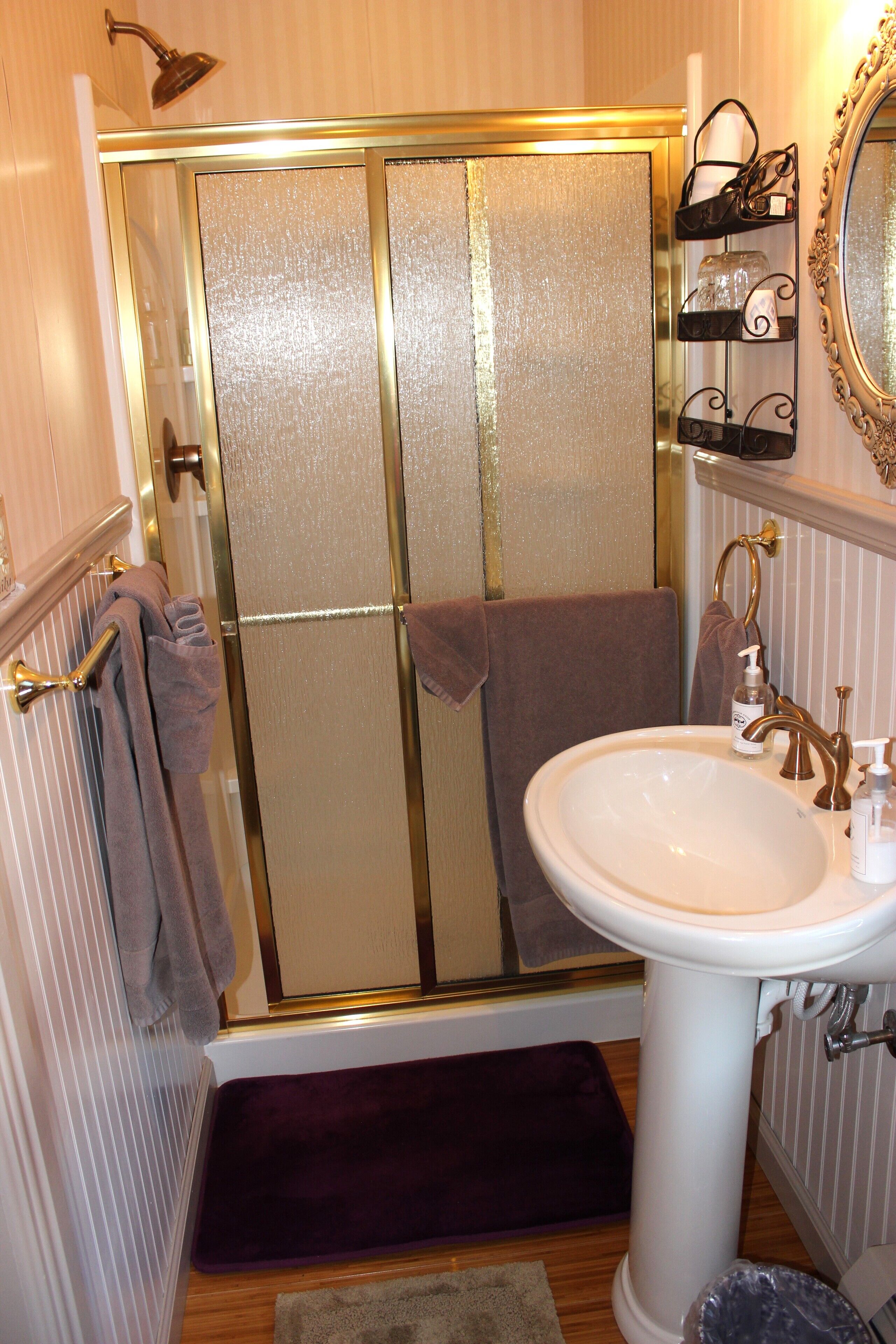 Een badkamer met een douche, een wastafel en een spiegel.