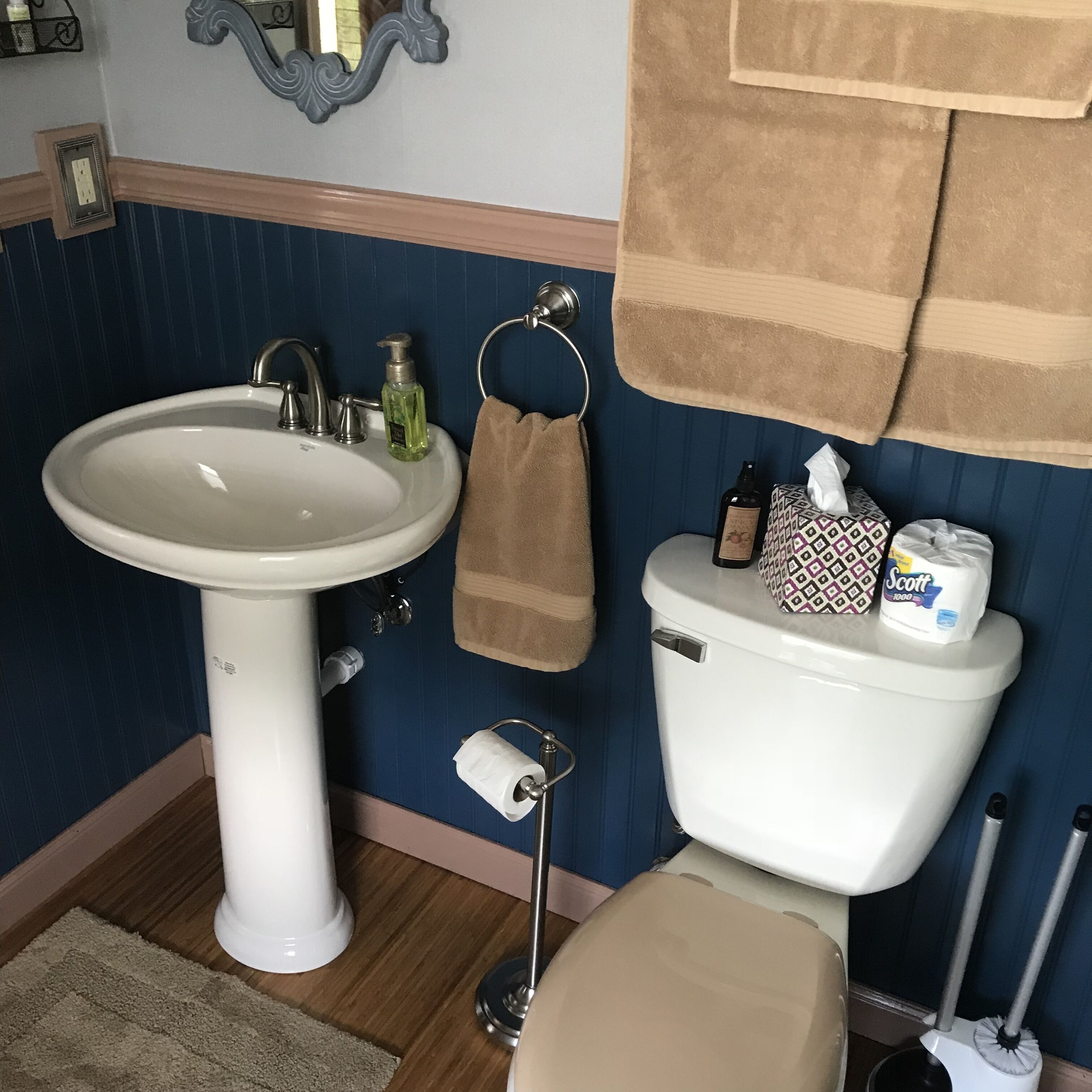 A bathroom with a white pedestal sink, a toilet, and a towel rack.