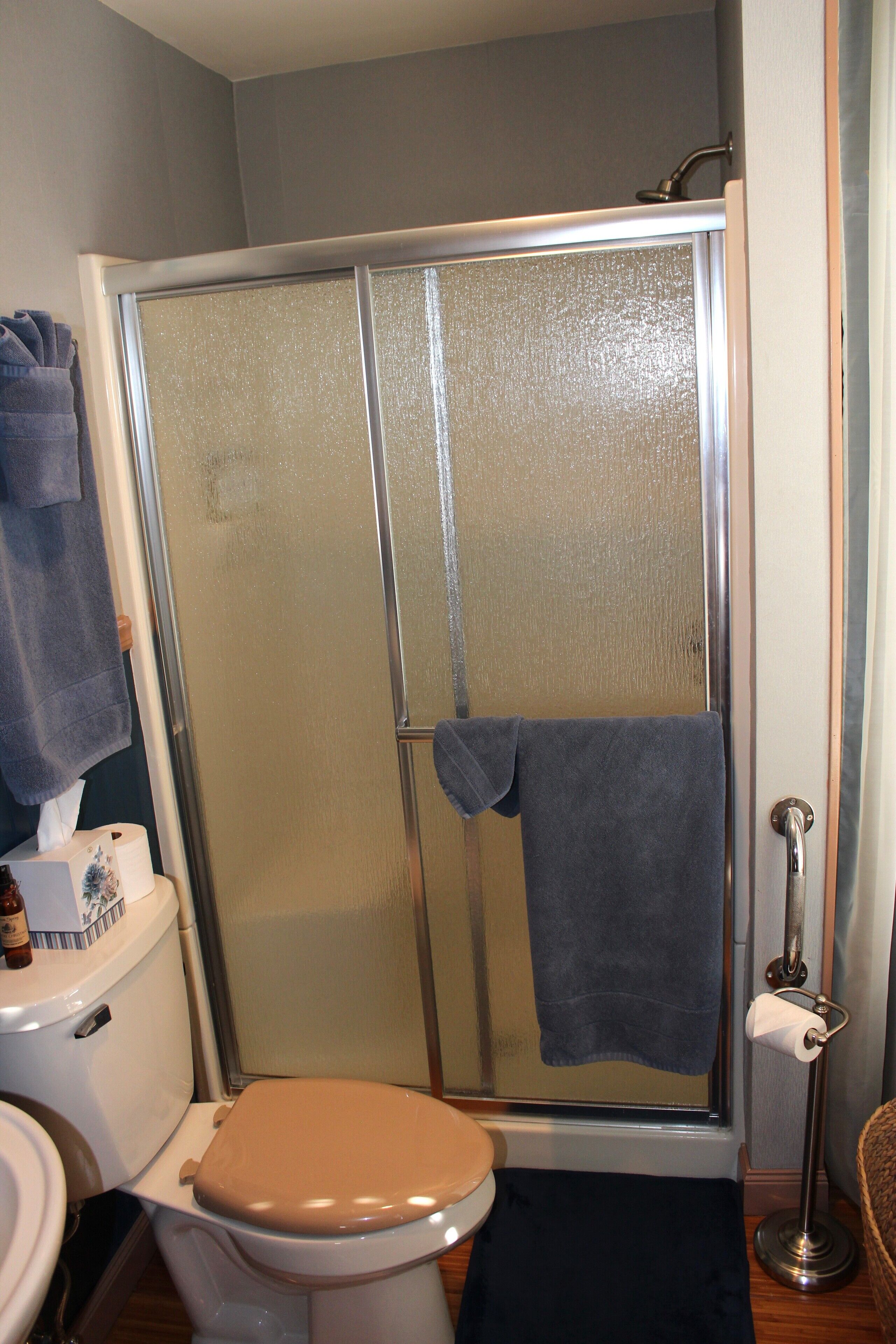 Un baño con inodoro, cabina de ducha y toallero.