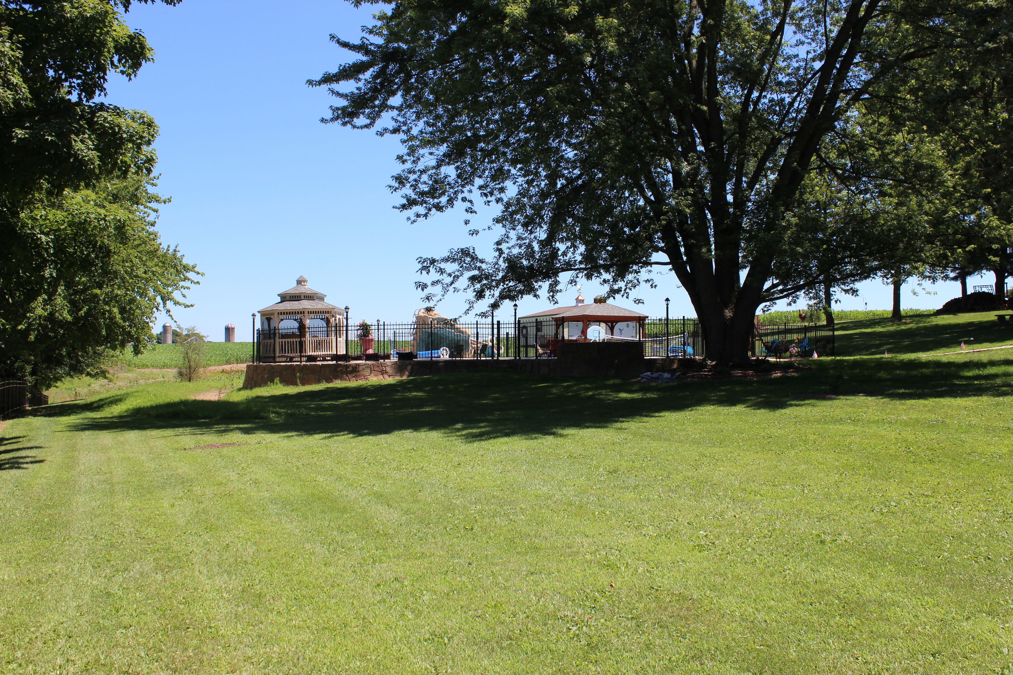 Un parco con un gazebo, un albero grande e una recinzione.