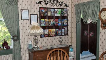 Una habitación con un aparador de madera, una lámpara, un tablón de anuncios con varias revistas y un reloj en la pared.