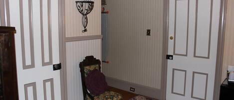 A hallway with a chair, a patterned rug, and two doors.
