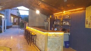 An outdoor bar area with a stone counter, bar stools, and shelves of bottles. - Villa Ozalp Apartments (Ortaca)