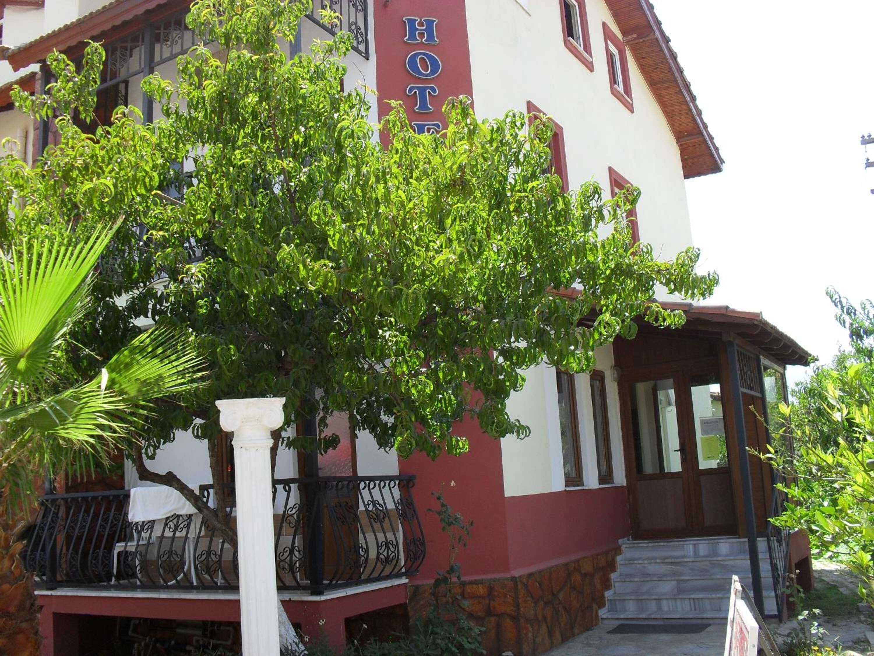 A hotel with a balcony, a staircase leading to the entrance, and a sign indicating it is a hotel.
