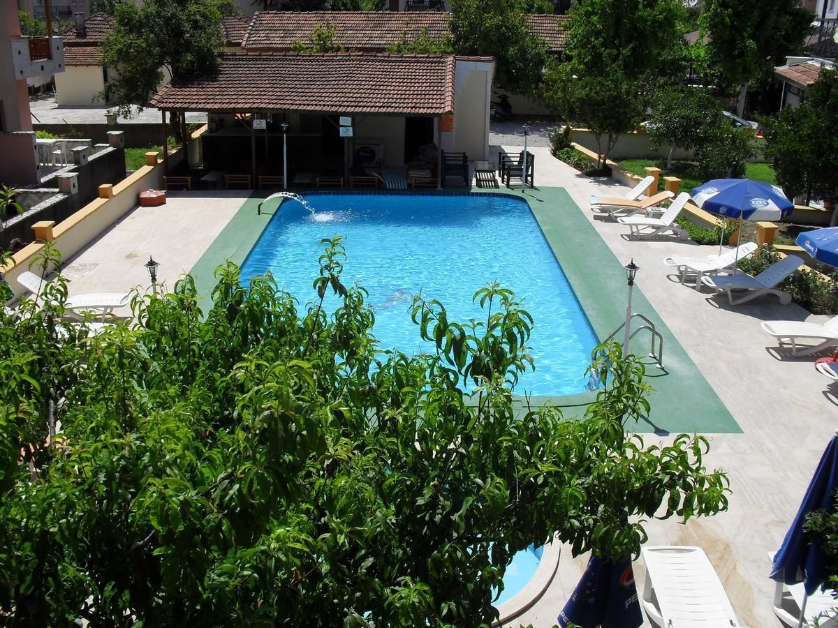 A rectangular swimming pool with a green deck, surrounded by lounge chairs and umbrellas.