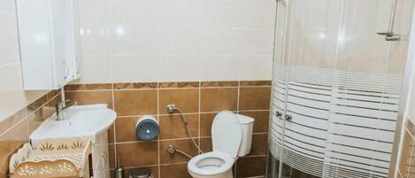 Een badkamer met een zwart-wit schakeerd vloer, toilet, wastafel en douchecabine.