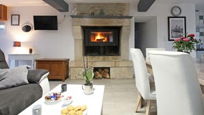 A living room with a stone fireplace, white furniture, and a dining area.