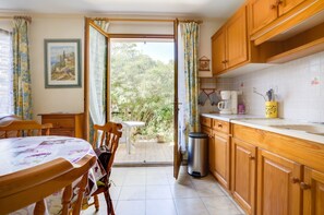 A kitchen with wooden cabinets, a coffee maker, and a trash bin. - Homerez - House in Agde (Agde)