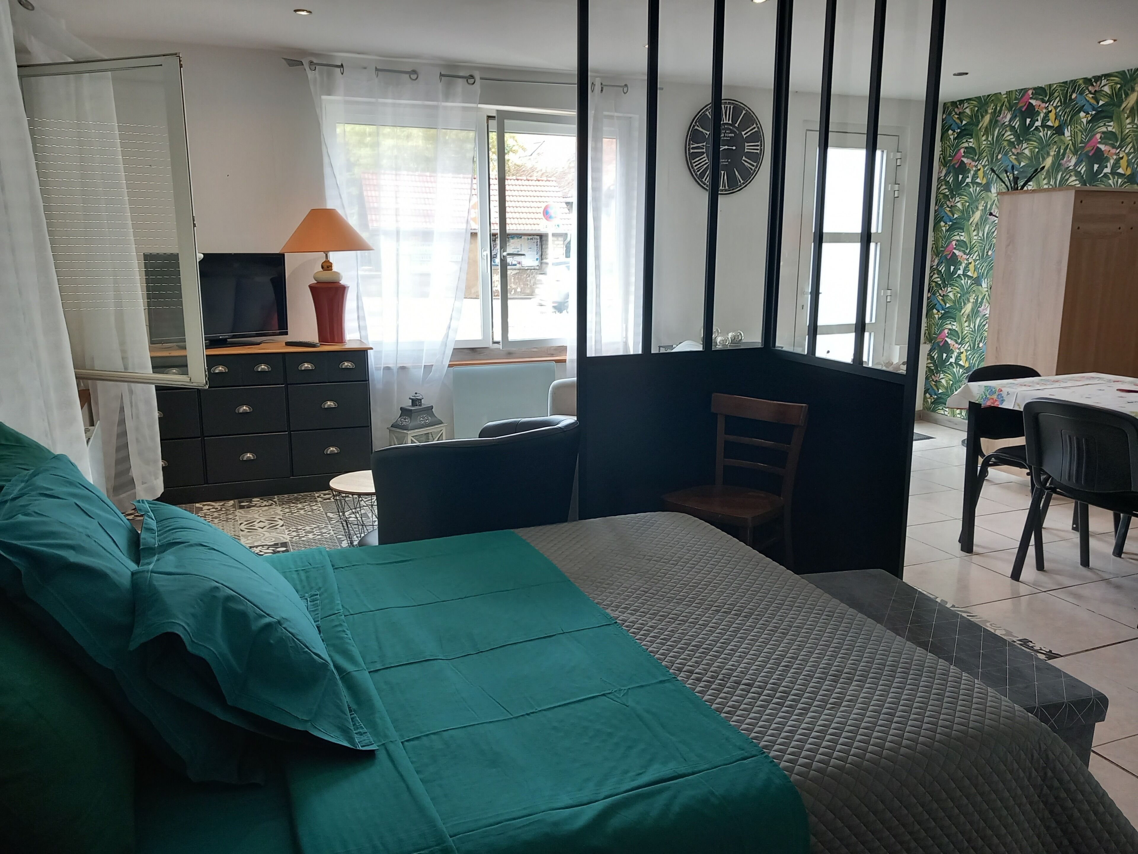 Een kamer met een bed, een bureau met lamp, een stoel en een eettafel.