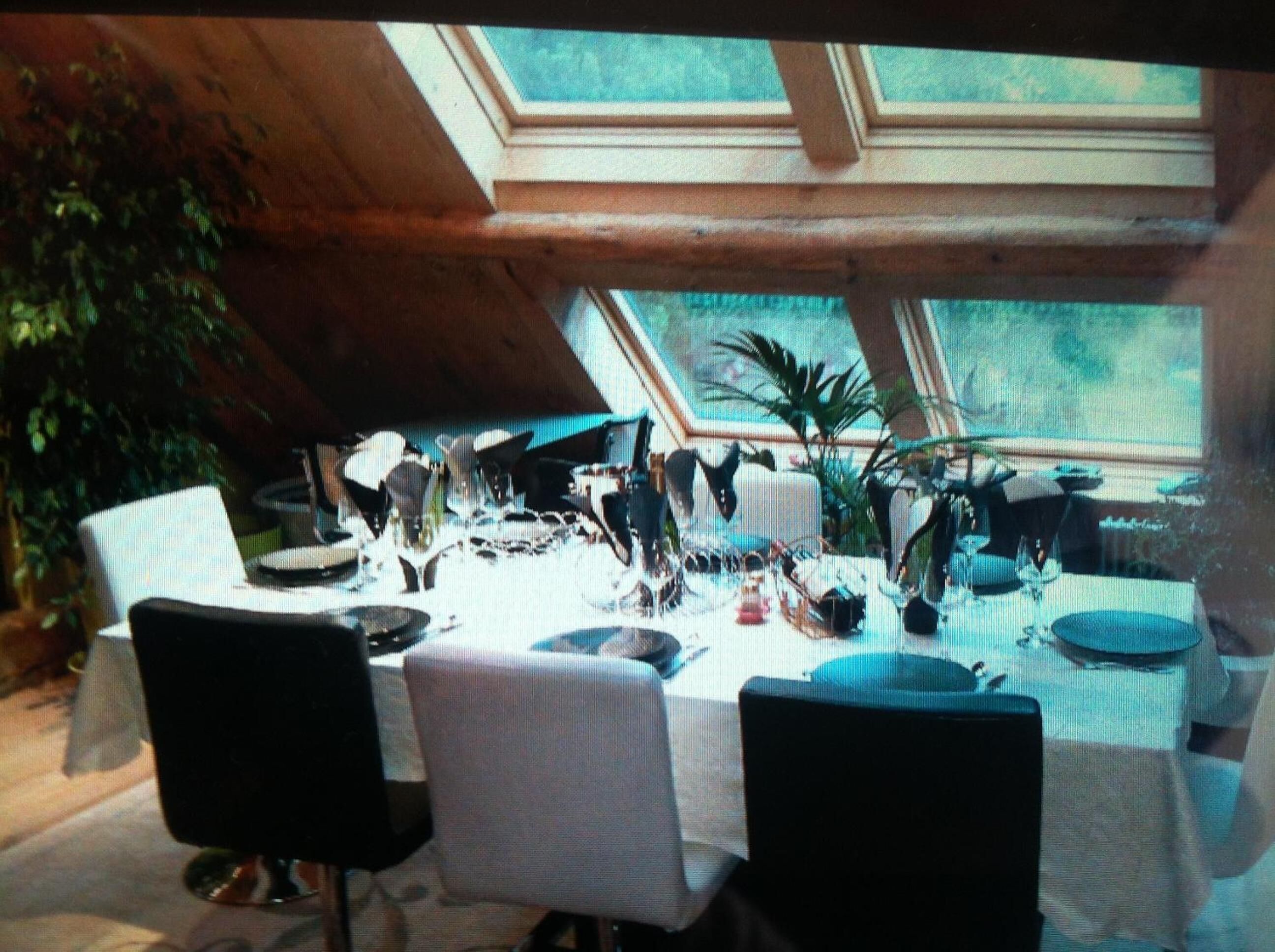 A dining area with a high ceiling and skylight, featuring a table set for four with chairs.