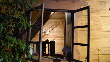Interior de madera con un amplio ventanal que da a una habitación con esquíes y una lámpara.