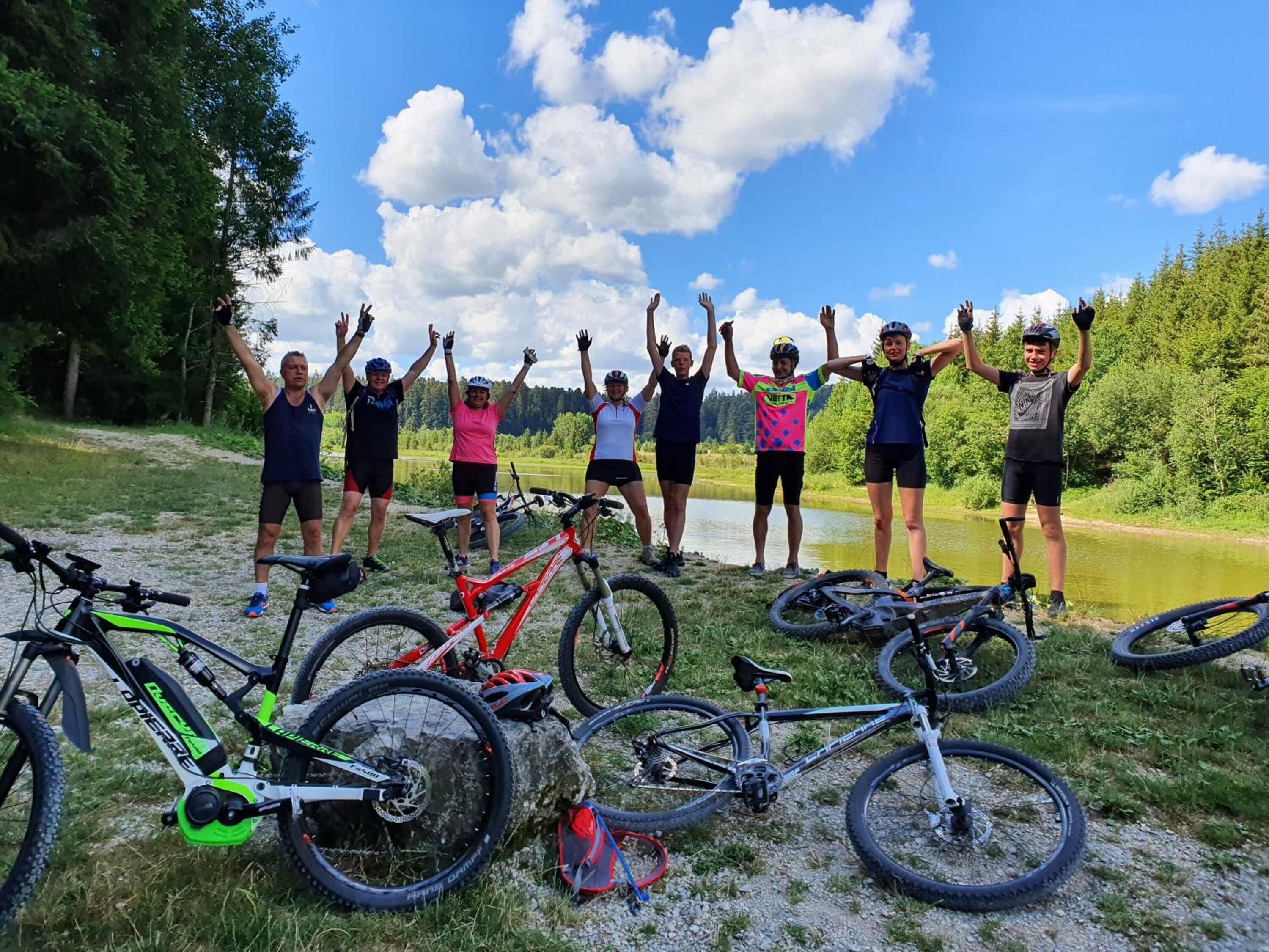 A group of people with bicycles in a natural setting, possibly a bike trail or park.
