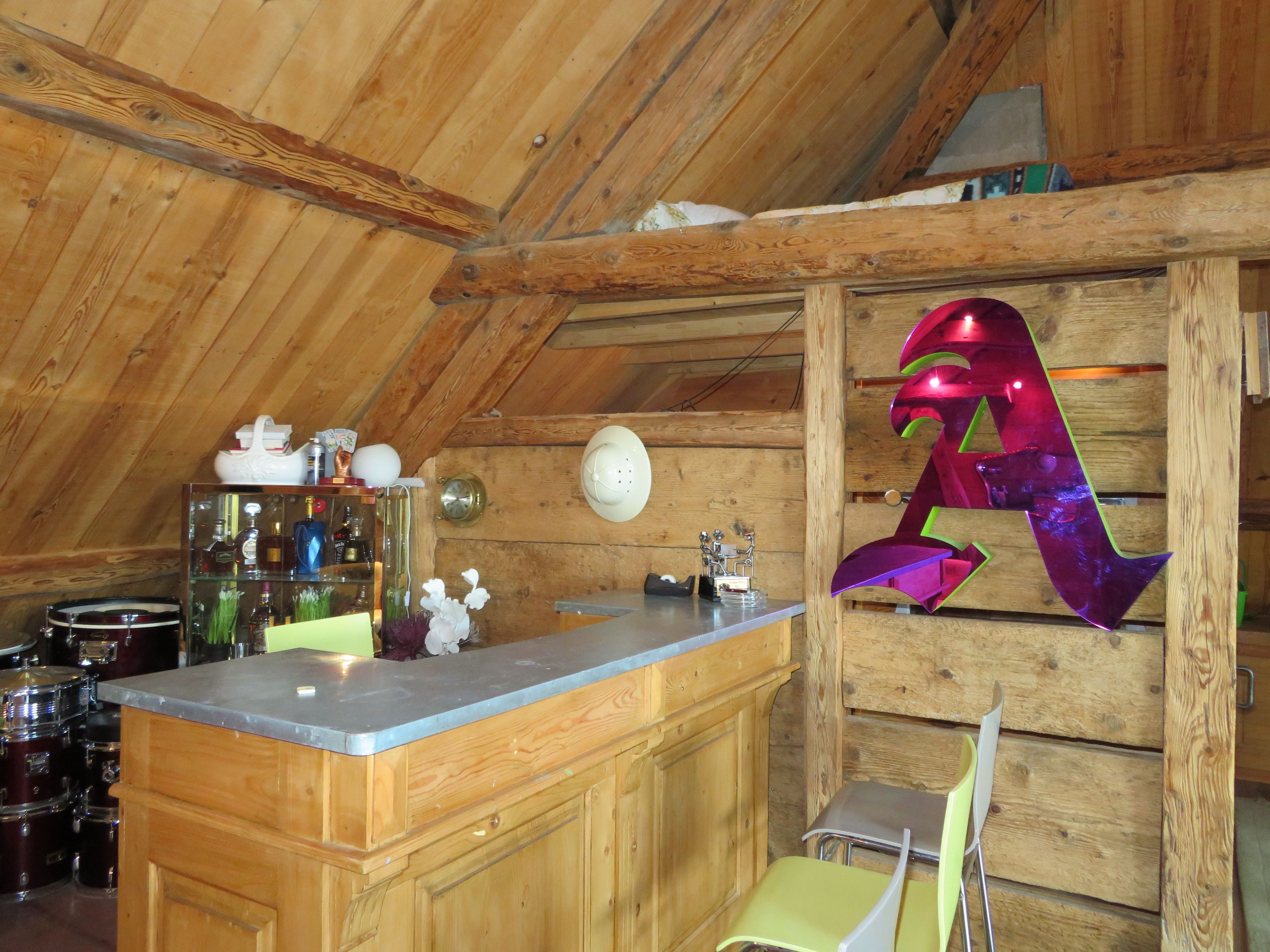 A rustic kitchen with wooden beams, a bar area, and a decorative metal sculpture.