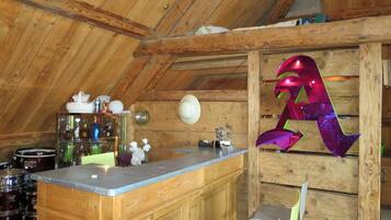 A rustic kitchen with wooden beams, a bar area, and a decorative metal sculpture.