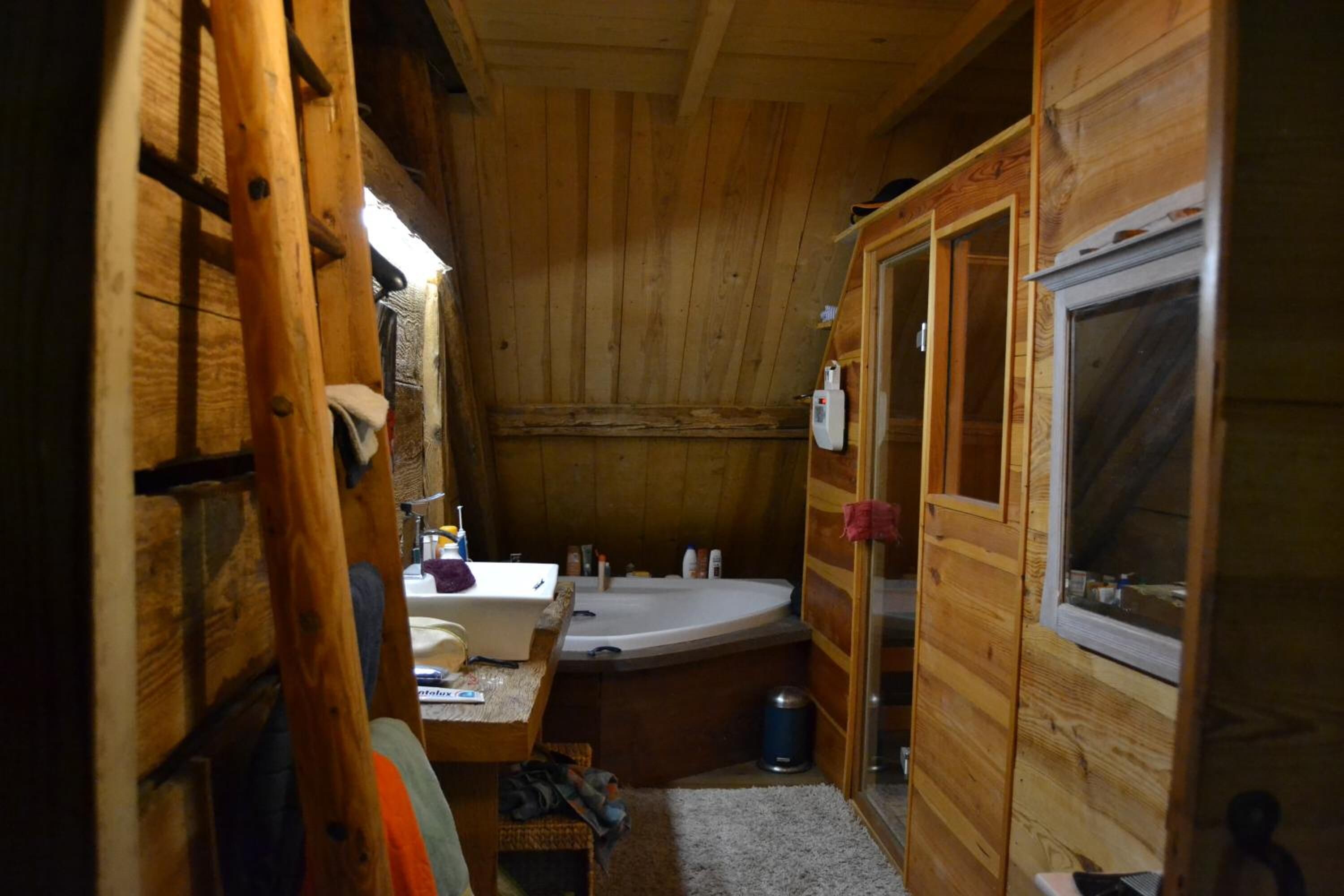 Ein Badezimmer einer Holzblockhütte mit einer Badewanne, einem Waschbecken und einem Fenster.
