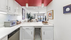 A modern kitchen with white cabinets, a built-in dishwasher, and a central island with a sink.