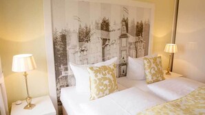 A hotel room with a large bed, two bedside tables with lamps, and a large framed picture on the wall. - Café & Hotel Daheim (Masserberg)