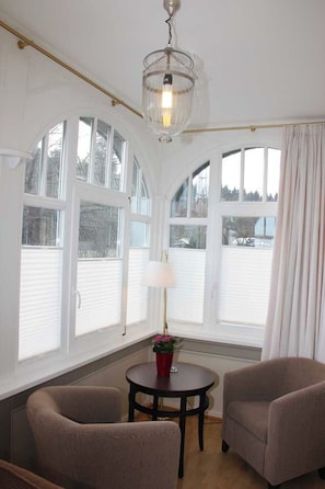 A room with a round table, two chairs, a lamp, and a chandelier. - Café & Hotel Daheim (Masserberg)