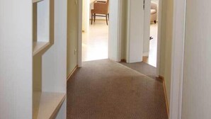 A hallway with a patterned carpet, white walls, and a ceiling light. There are doors leading to other rooms. - Café & Hotel Daheim (Masserberg)