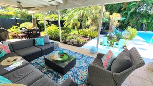 An outdoor patio with a sofa, chairs, and a pool.