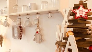 A kitchen counter with a cake on a glass stand, a wooden cutting board with a pine cone, and a Christmas ornament. - Haus am See B&B (Bornheim)