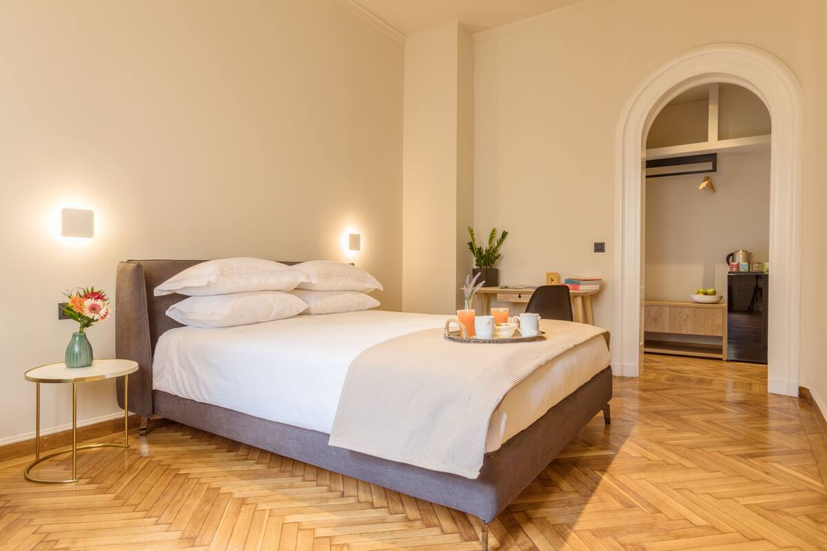 A neatly arranged bedroom with a bed, bedside table, and a small desk area.